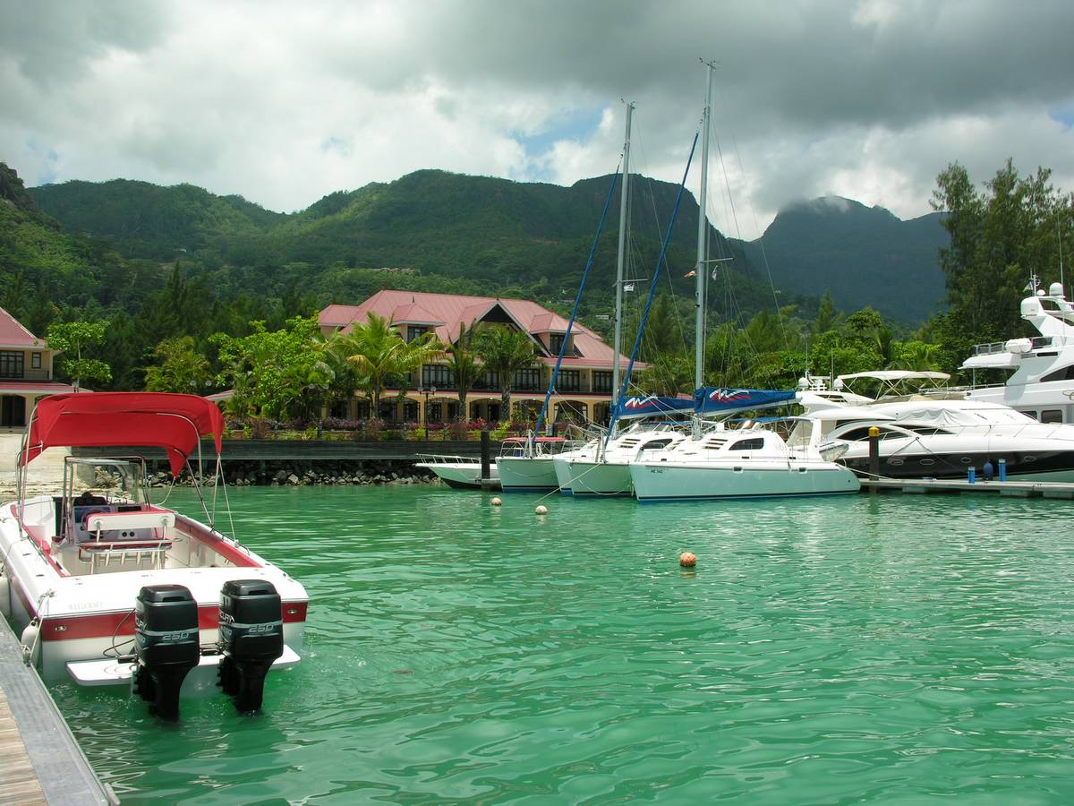 Des bateaux amarrés dans une marina de Mahé, au pied de montagnes verdoyantes