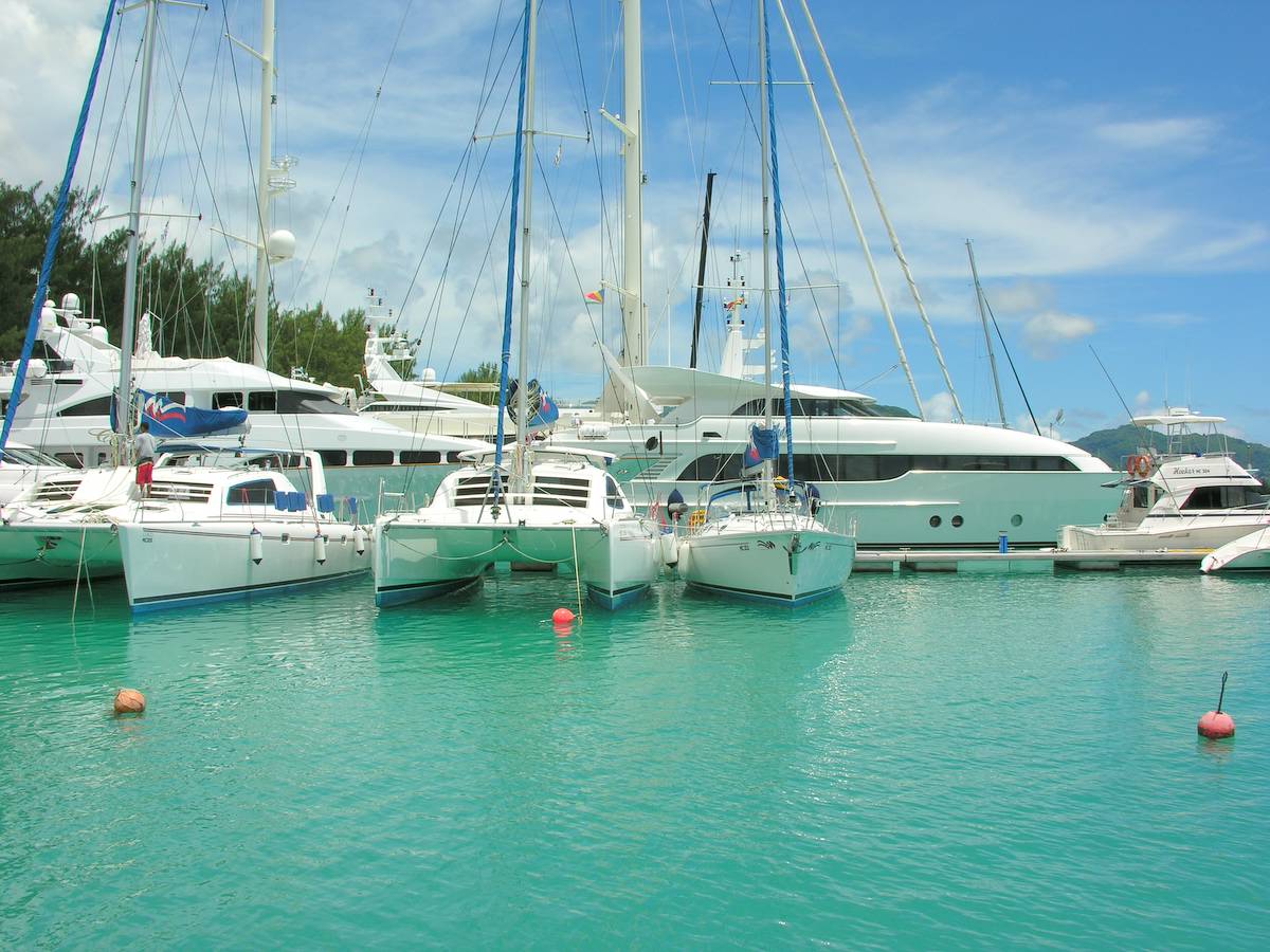 Des yachts et des catamarans amarrés dans une eau turquoise, dans une marina de Mahé