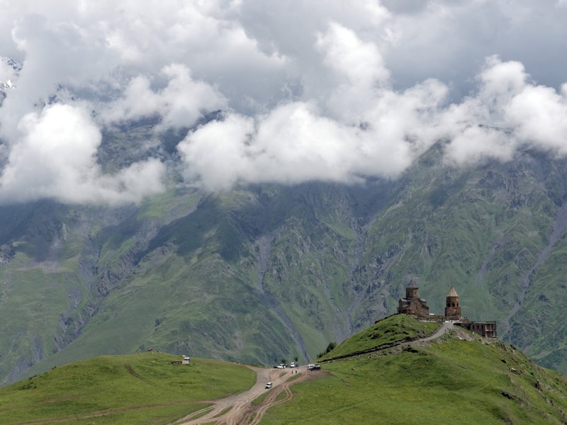 Gergeti Trinity Church on a hilltop below cloud-covered mountains near Kazbegi, Georgia